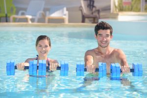 A couple using water weights in an outdoor pool