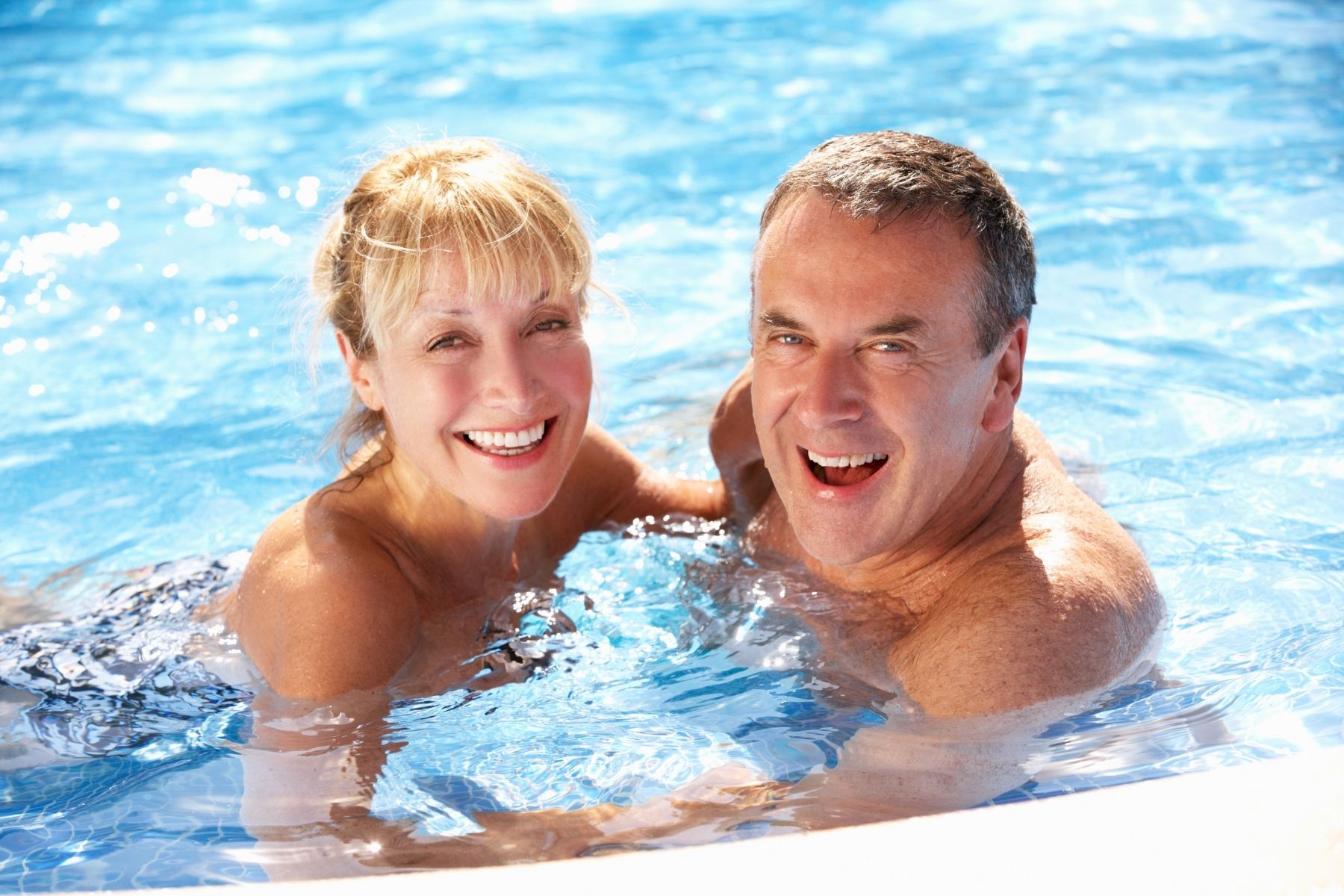 senior couple swimming in home swimming pool